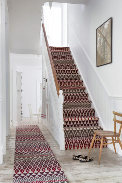 Staircase featuring a red and beige patterned carpet with a matching hallway runner